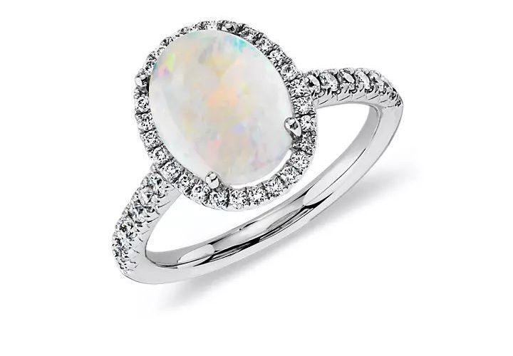 A white cabochon cut opal engagement ring with diamond pave accents